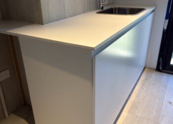 Módulo superior de cocina en madera con iluminación LED rasante sobre mesada blanca