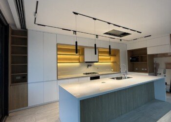 Isla de cocina a medida con mesada blanca en inglete y anafe vitrocerámico integrado.