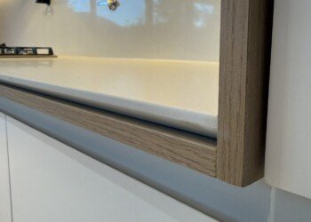 Detalle de terminación en marco de madera con perfil LED embutido y mesada ingletada en cocina a medida