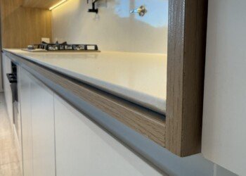 Encuadre de alacena en madera e iluminación LED cálida sobre mesada blanca para obra residencial