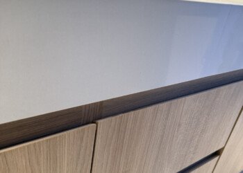 Vanitory a medida en madera clara con mesada blanca ingletada y bacha bajo mesada para obra residencial.