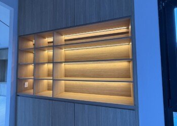 Mueble de guardado de piso a techo en madera con estantes e iluminación LED integrada para obra residencial