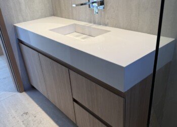 Mobiliario de baño en carpintería técnica combinado con mesada de faldón alto y espejo retroiluminado