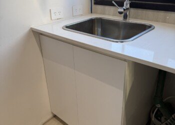 Mueble de lavadero bajo mesada con bacha de acero inoxidable y mesada blanca en carpintería técnica