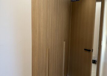 Frente de placard de piso a techo y puerta de paso a juego en madera clara para obra residencial