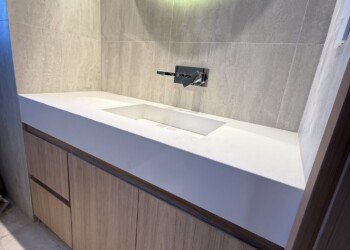 Vanitory a medida en madera clara con espejo circular retroiluminado con luz LED cálida para baño moderno