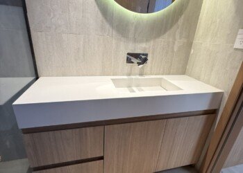 Detalle de antebaño con mobiliario en carpintería a medida y espejo redondo con iluminación LED integrada